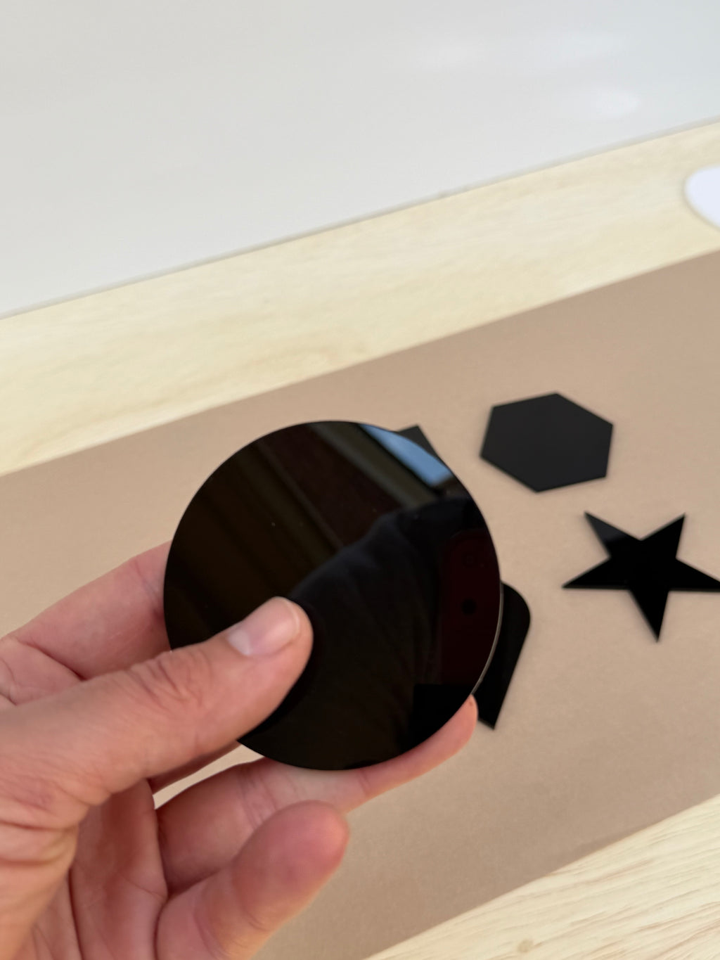 Black 1/8 inch acrylic circle blank for UV printing held in hand to show size