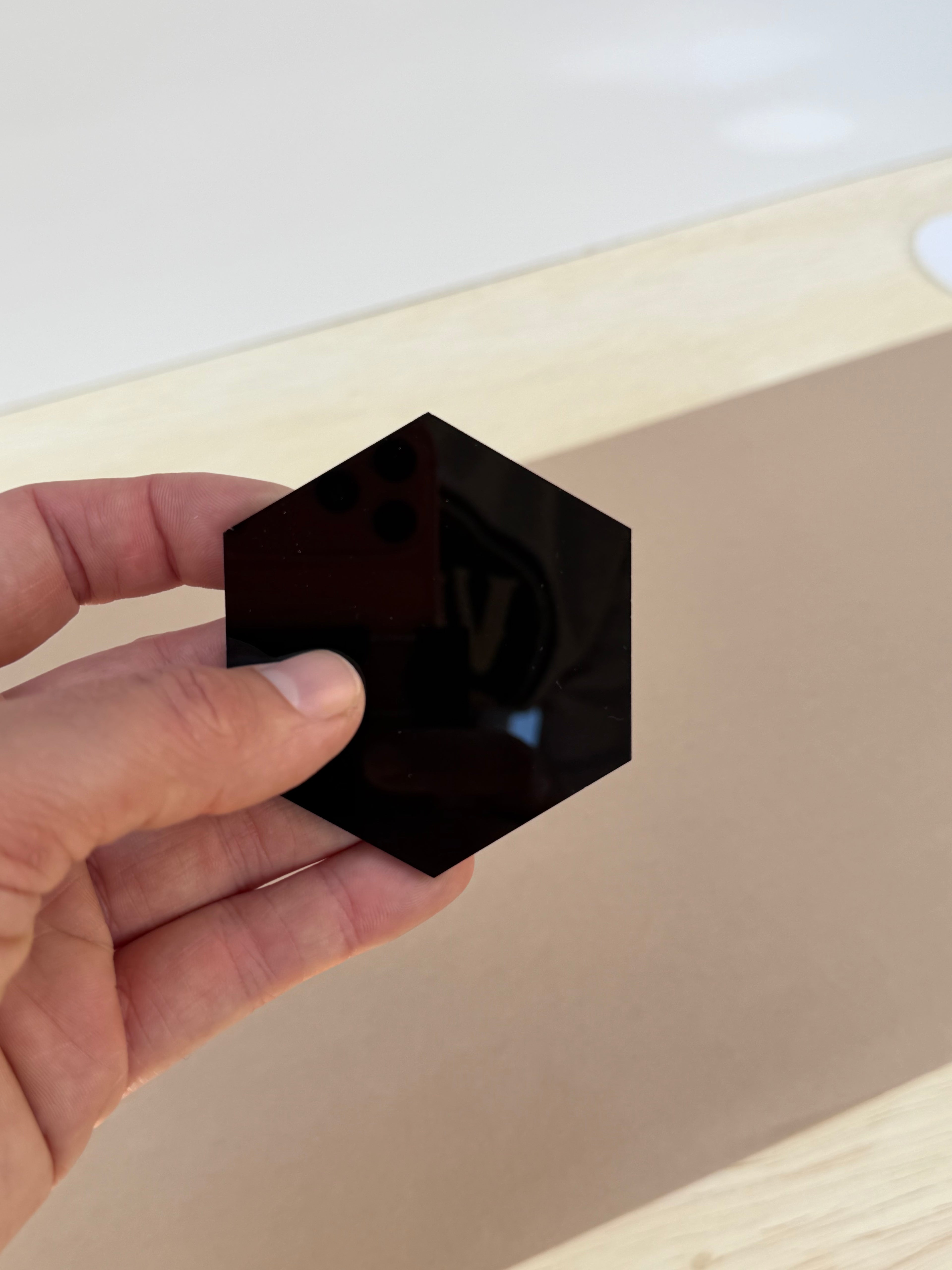 Black 1/8 inch acrylic hexagon blank for UV printing held in hand to show size