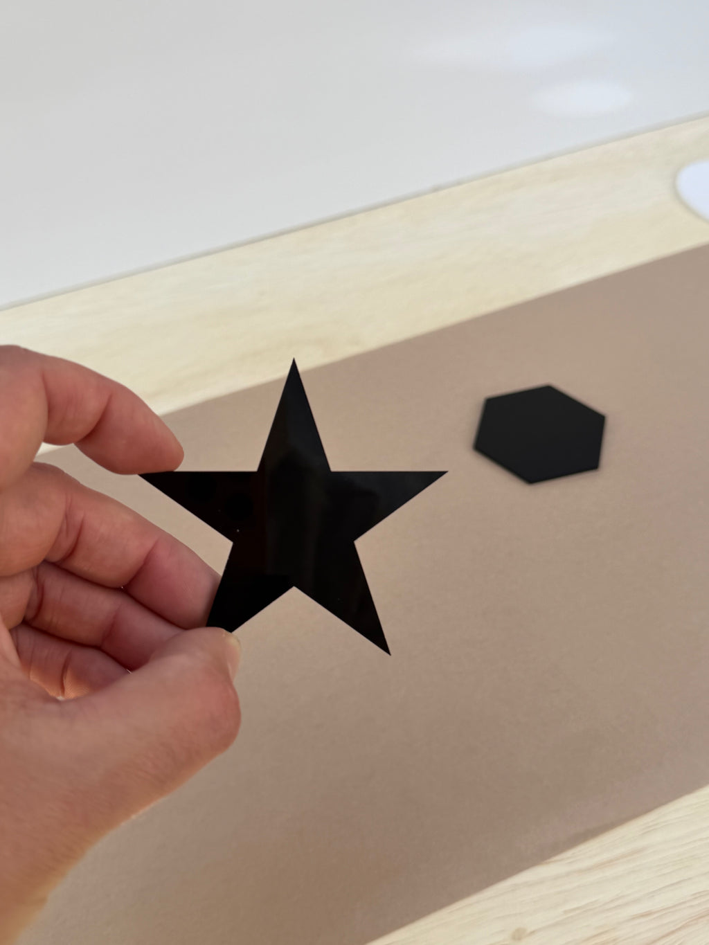 Black 1/8 inch acrylic star blank for UV printing held in hand to show size