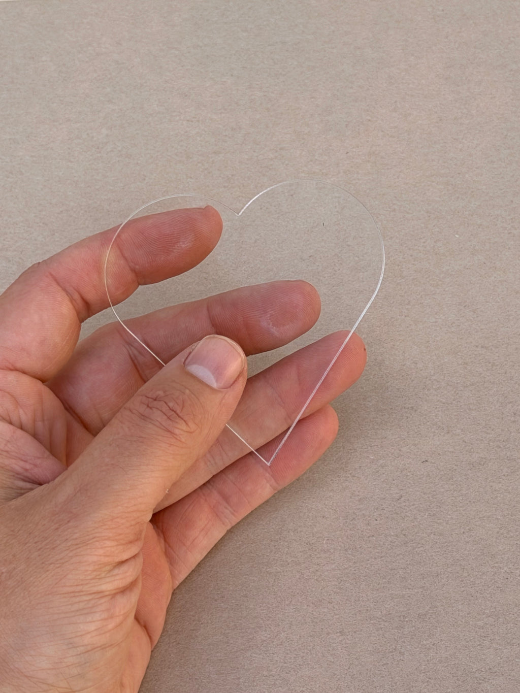 1/8 inch clear acrylic heart blank held in hand to show size