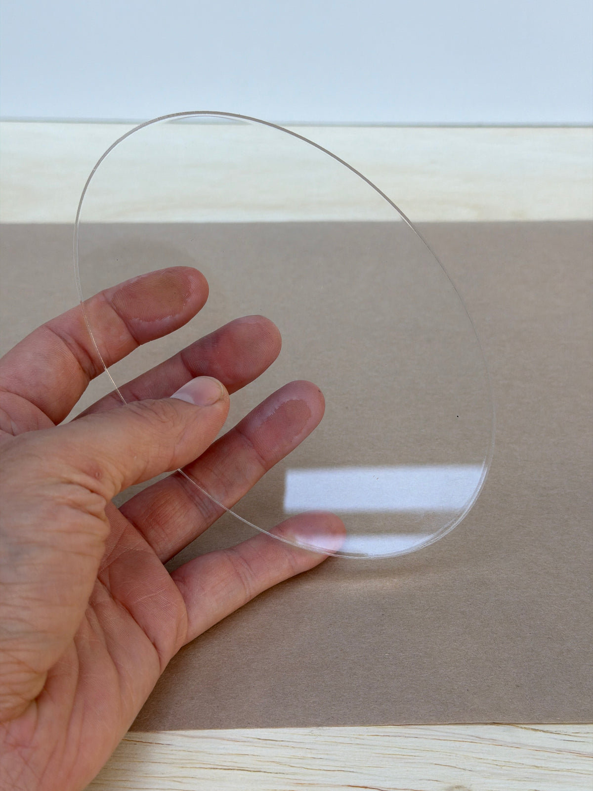 1/4 inch clear acrylic oval blank held in hand to show size