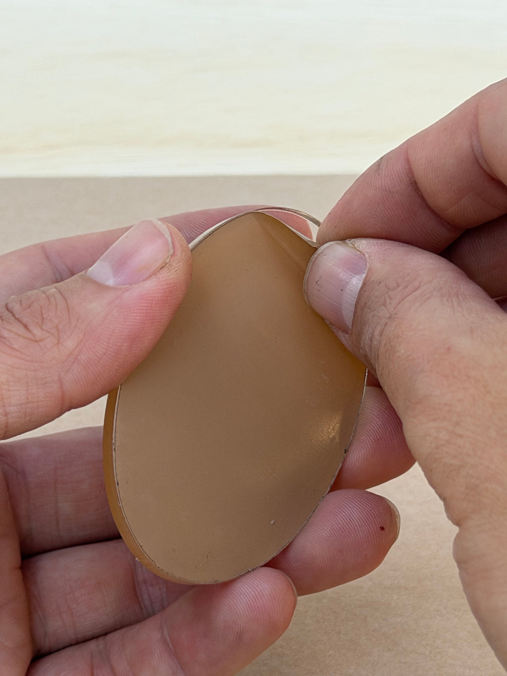 1/8 inch acrylic oval blank with protective film, held in hand