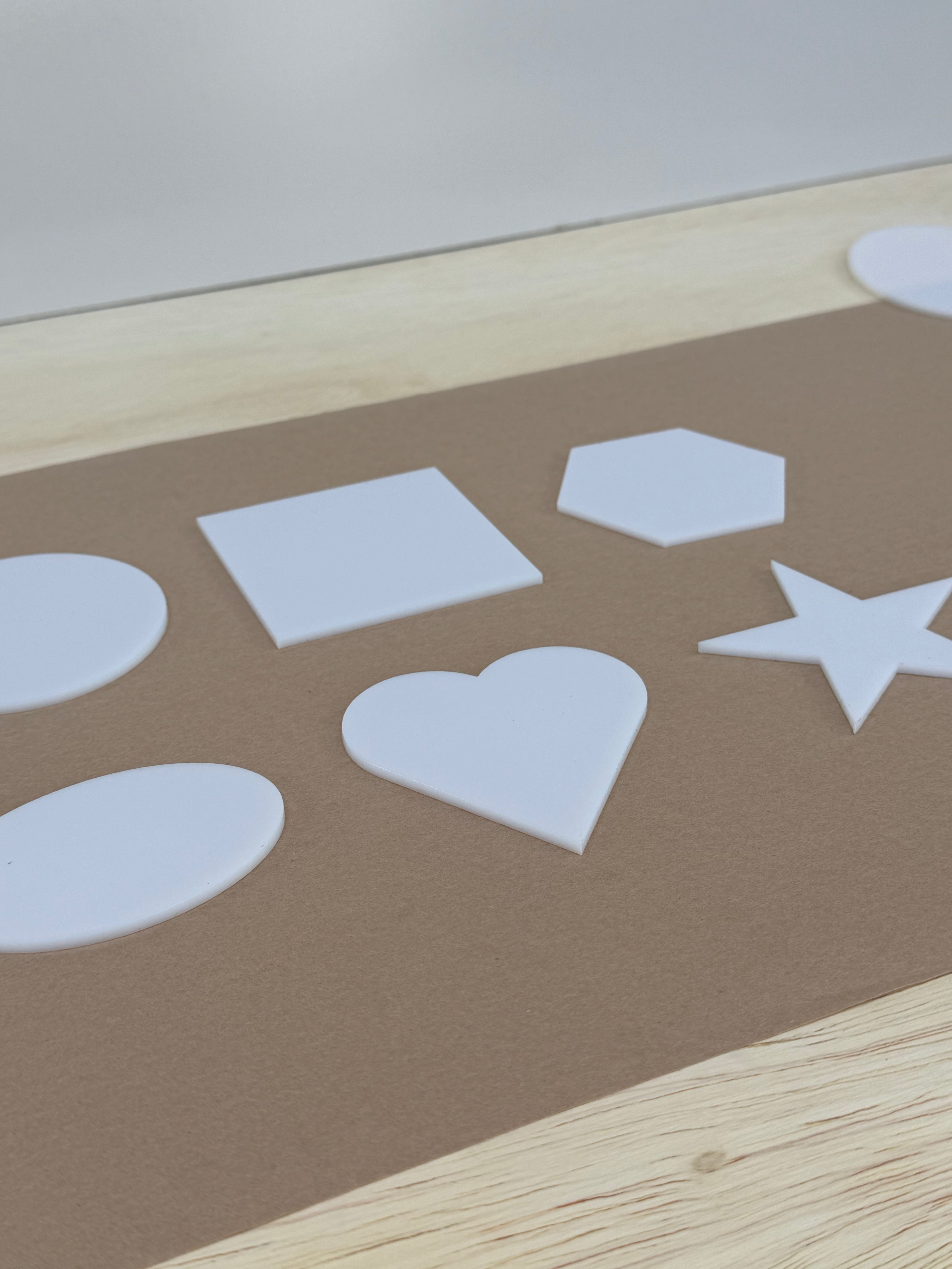 White acrylic UV printing blanks in six shapes shown at an angle