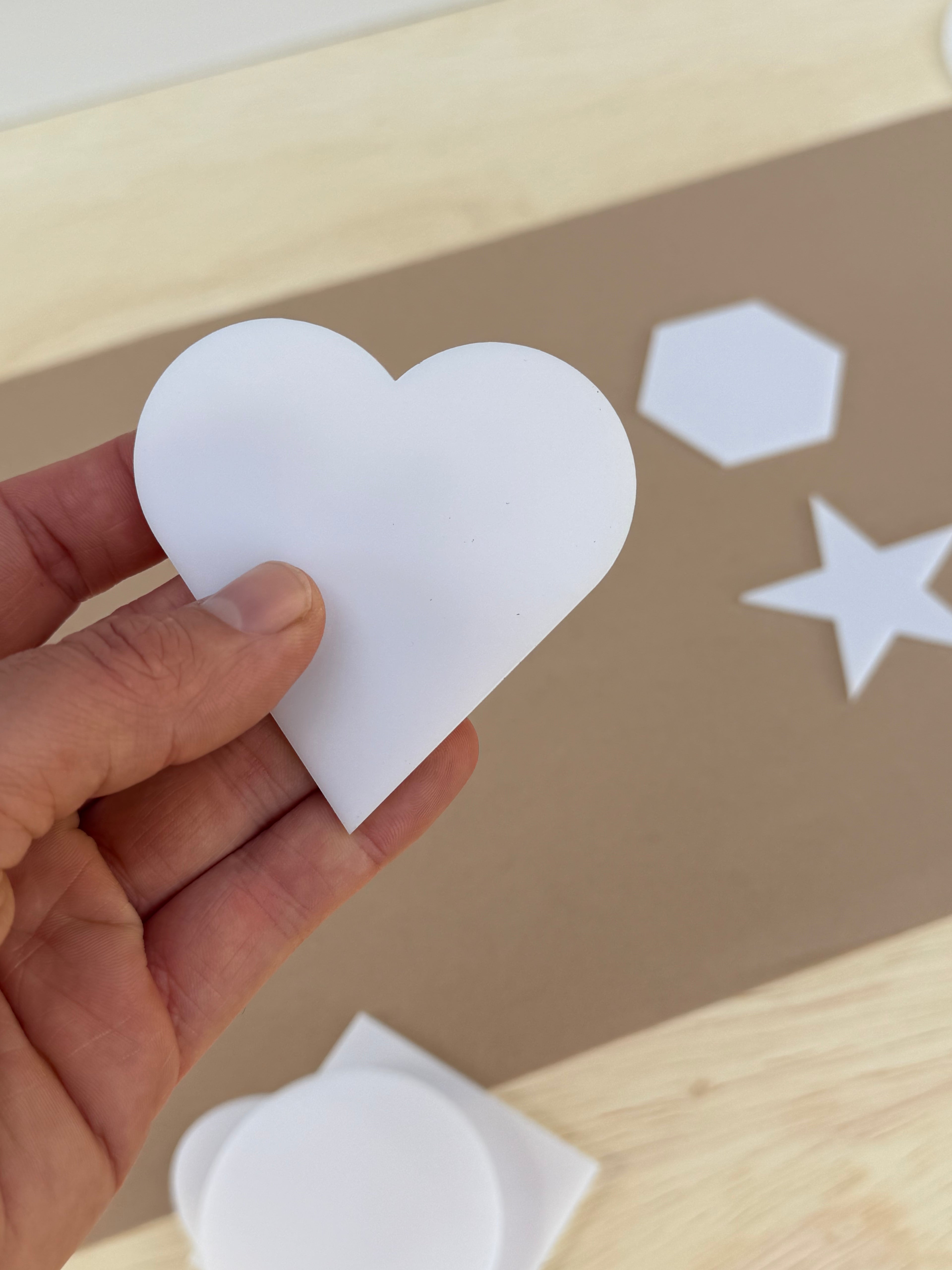 White 1/8 inch acrylic heart blank for UV printing held in hand to show size
