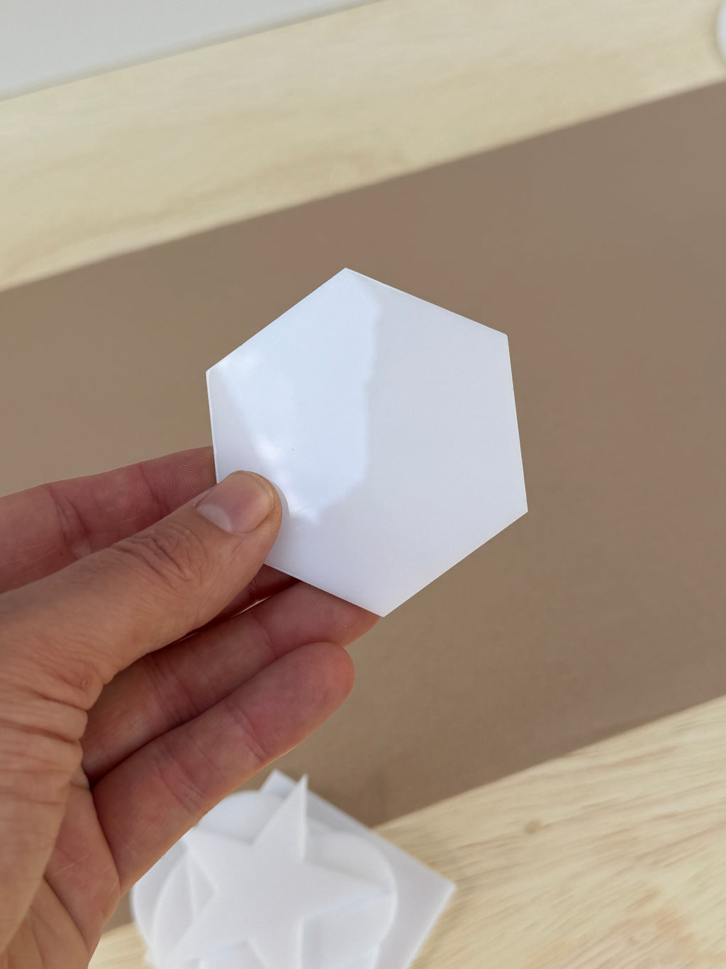 White 1/8 inch acrylic hexagon blank for UV printing held in hand to show size