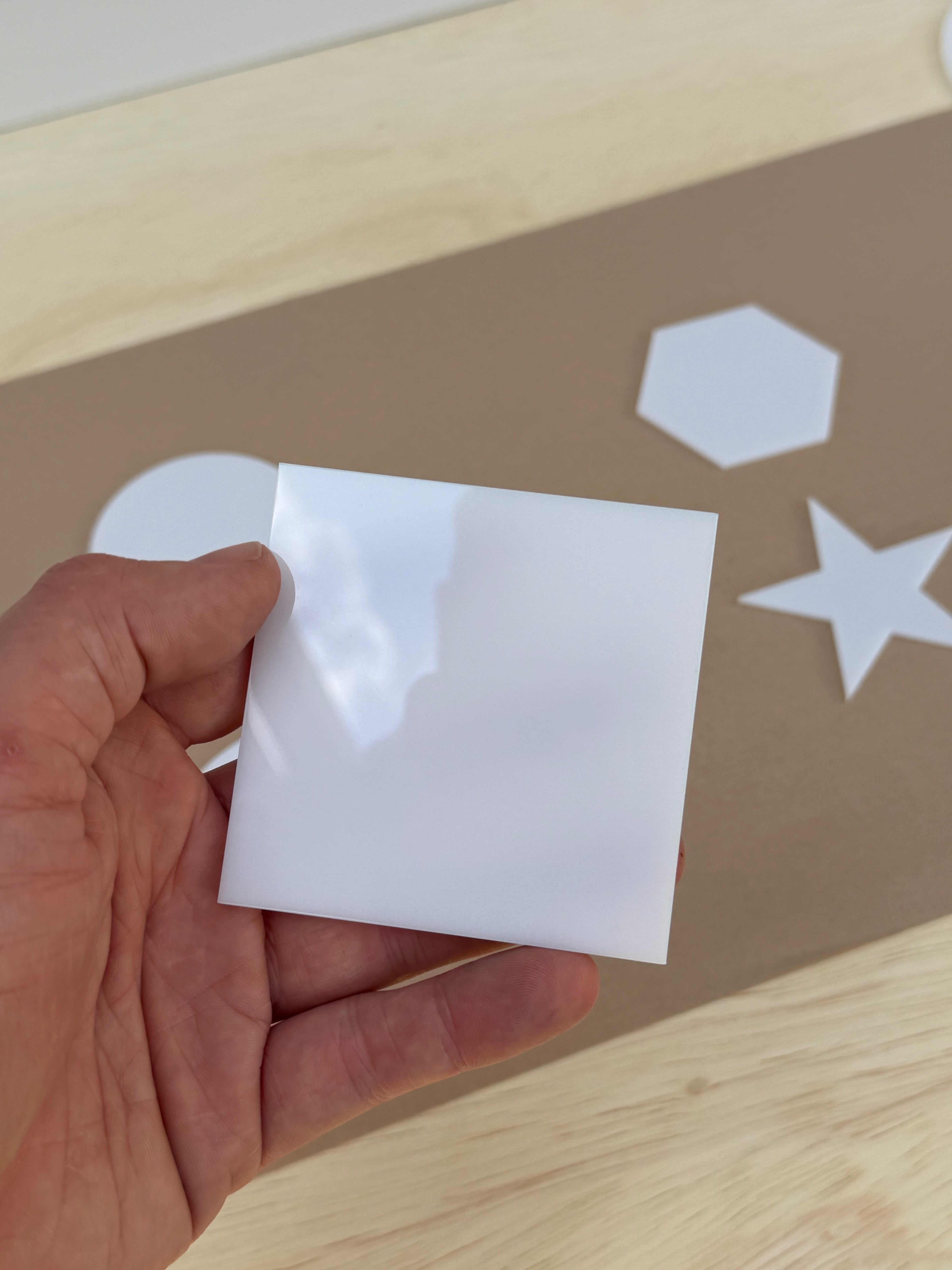 White 1/8 inch acrylic square blank for UV printing held in hand to show size