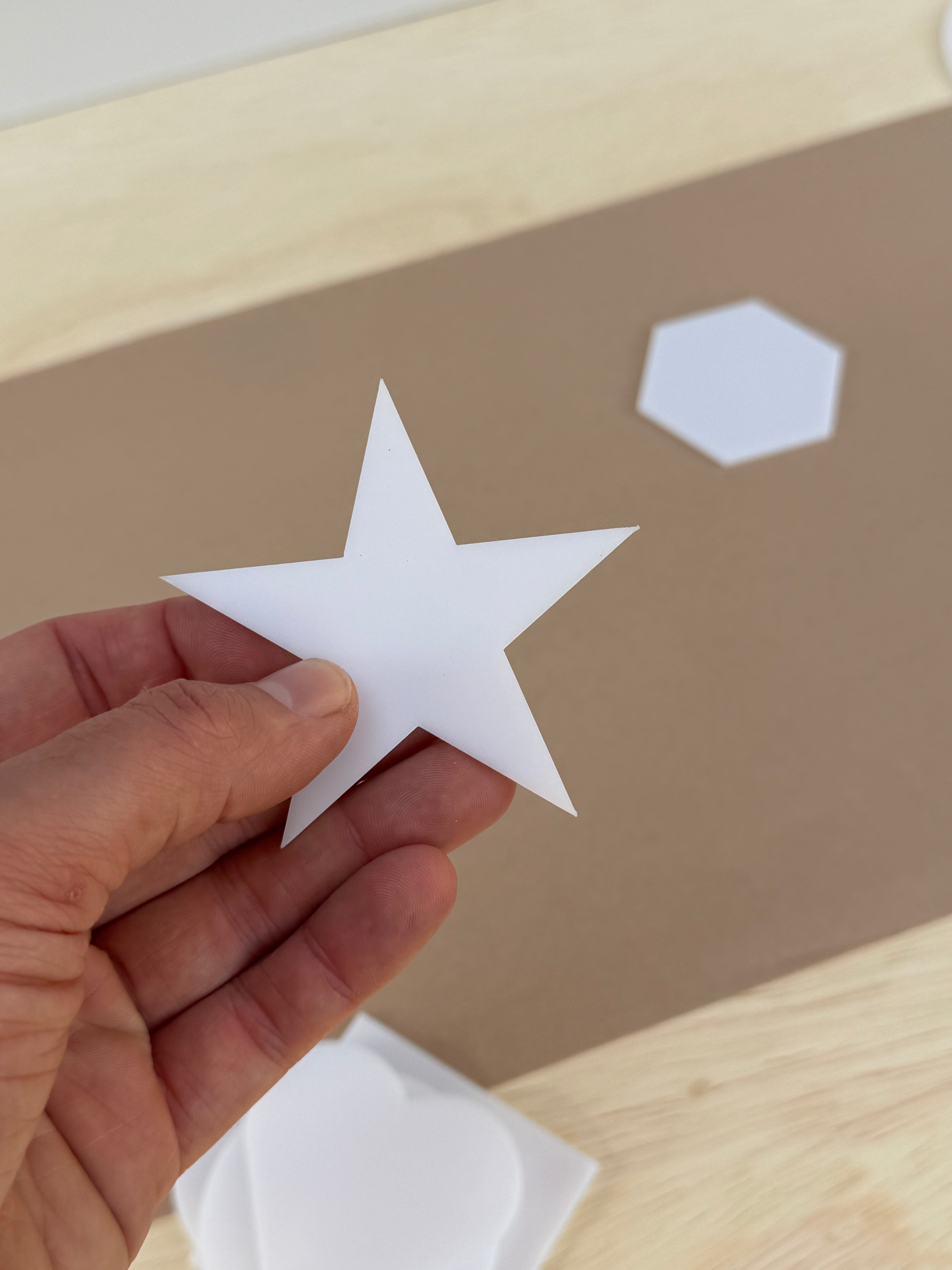 White 1/8 inch acrylic star blank for UV printing held in hand to show size